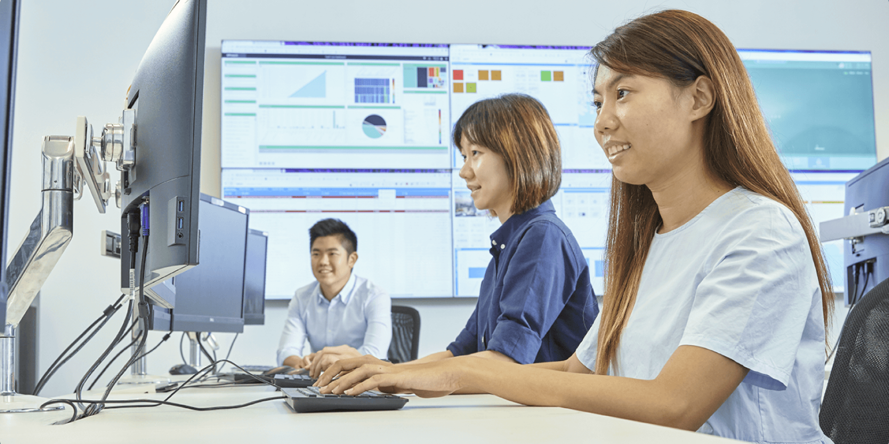 Professionals working at computers with dashboards displayed on screens